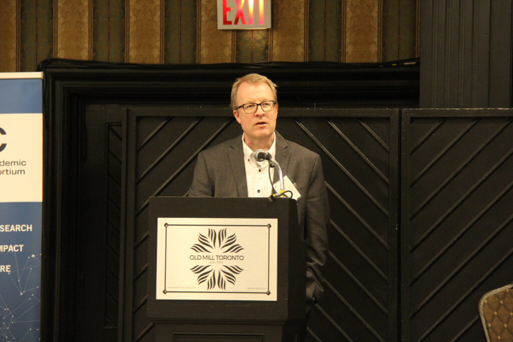 Scott Gray-Owen speaking at a podium