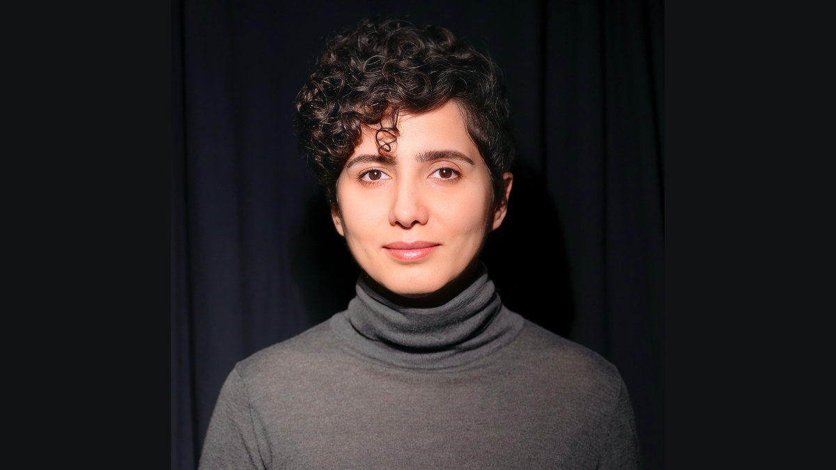 Saeedeh Moayedi-Nia wearing a grey turtleneck against a black backdrop