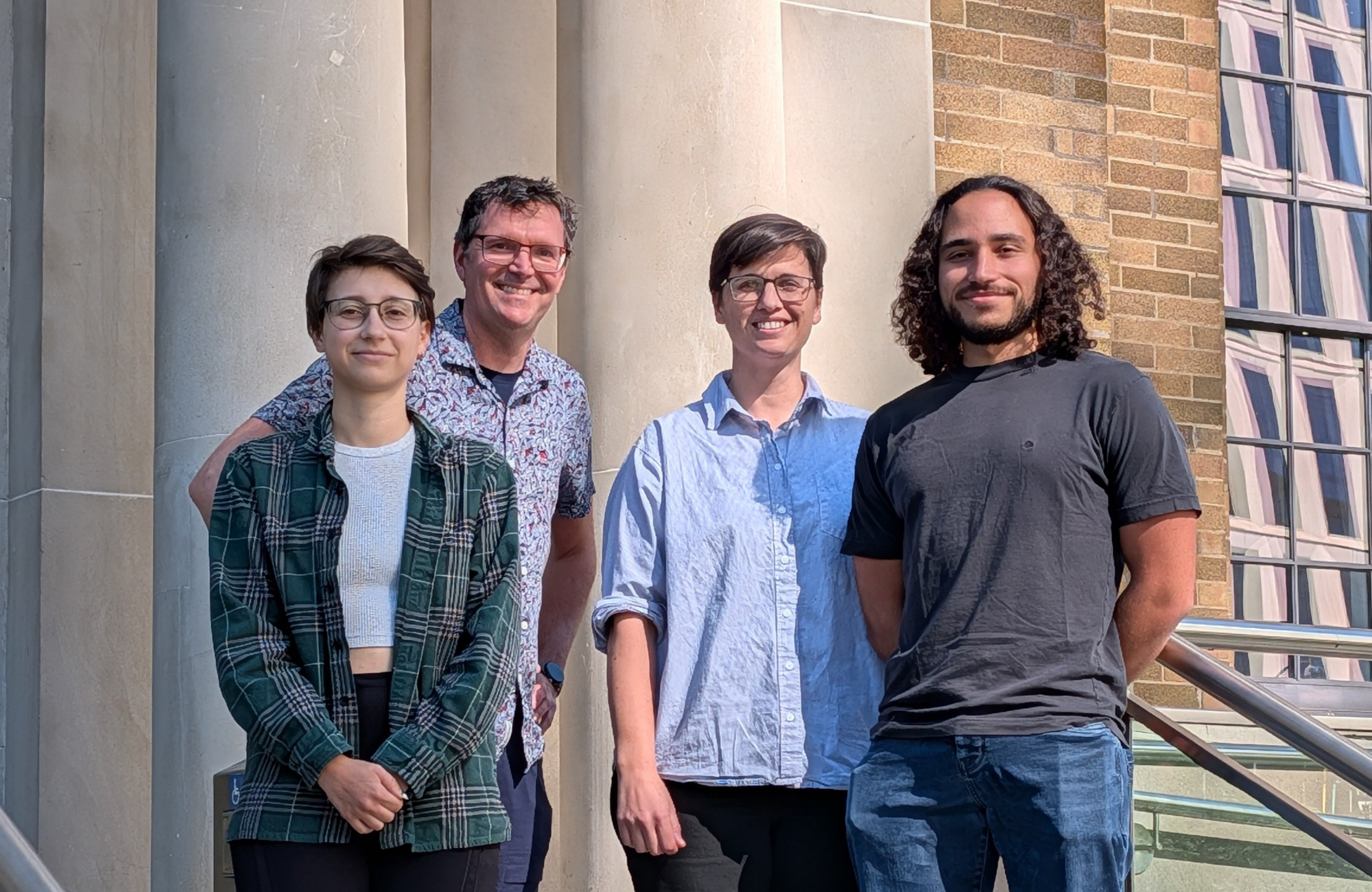 A smiling woman with a grey sweater and a smiling man wearing a toque and blue coat
